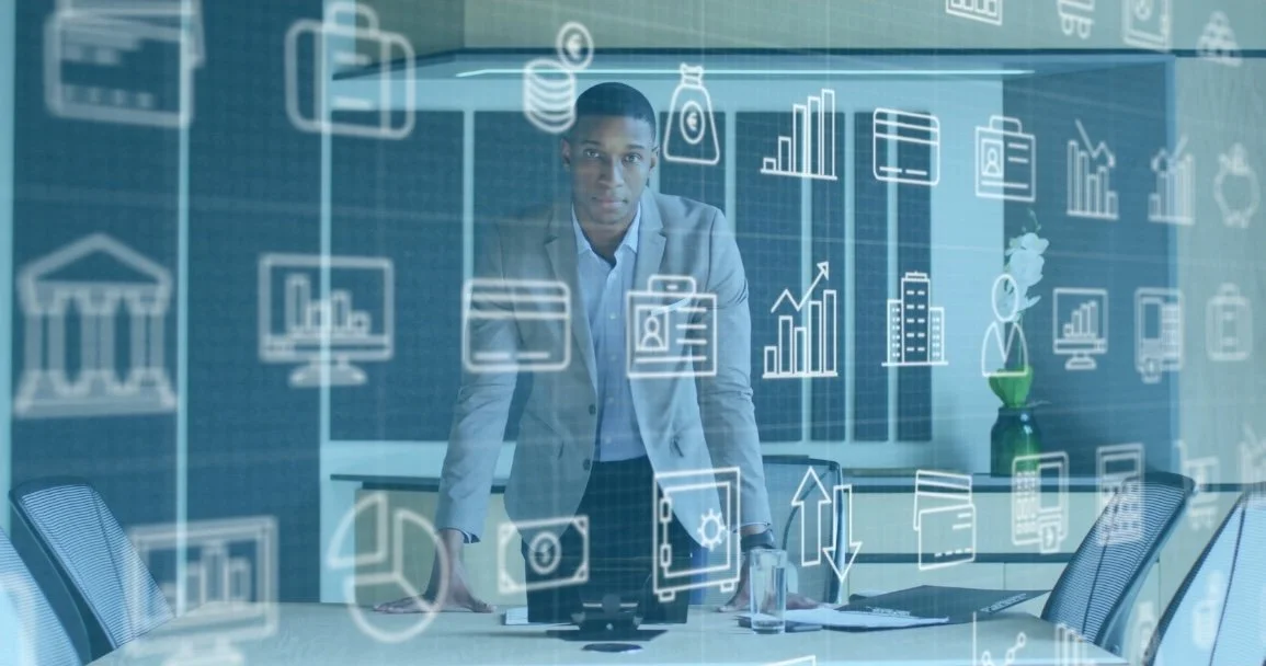 A man in a gray suit leans forward on a conference table with documents, a glass of water, and a laptop. The image has an overlay of digital icons representing data, graphs, charts, and business-related symbols.