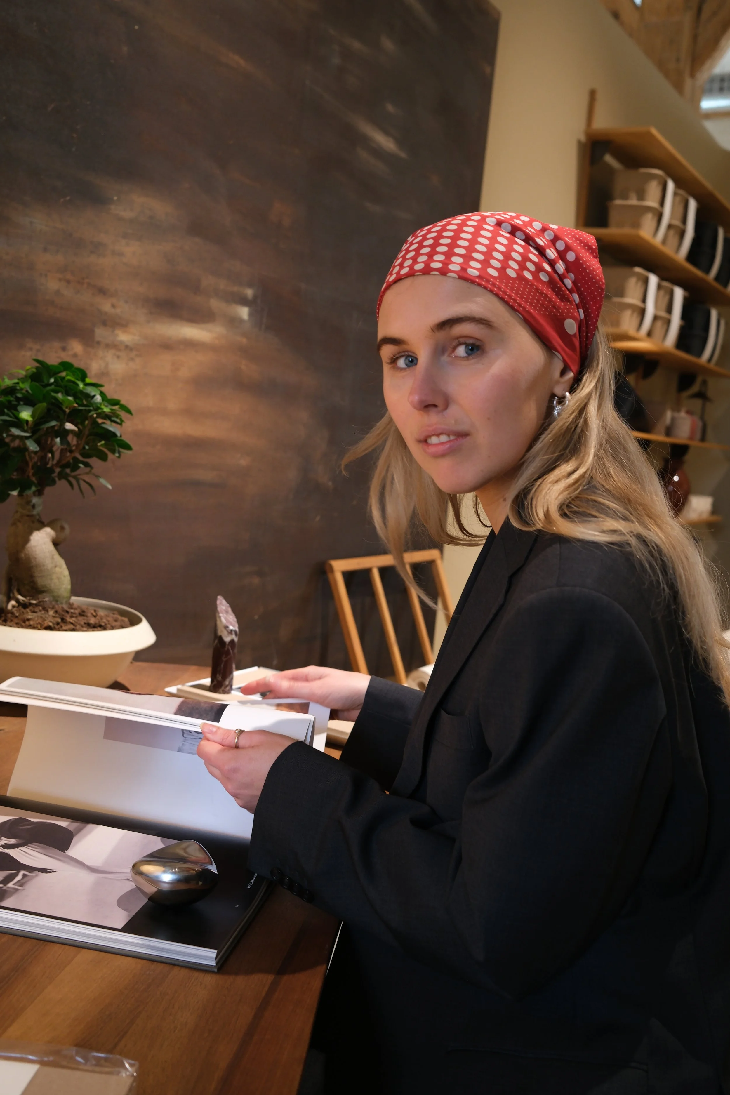 Books, a mug, and a magazine are on a bed with a gray sheet.