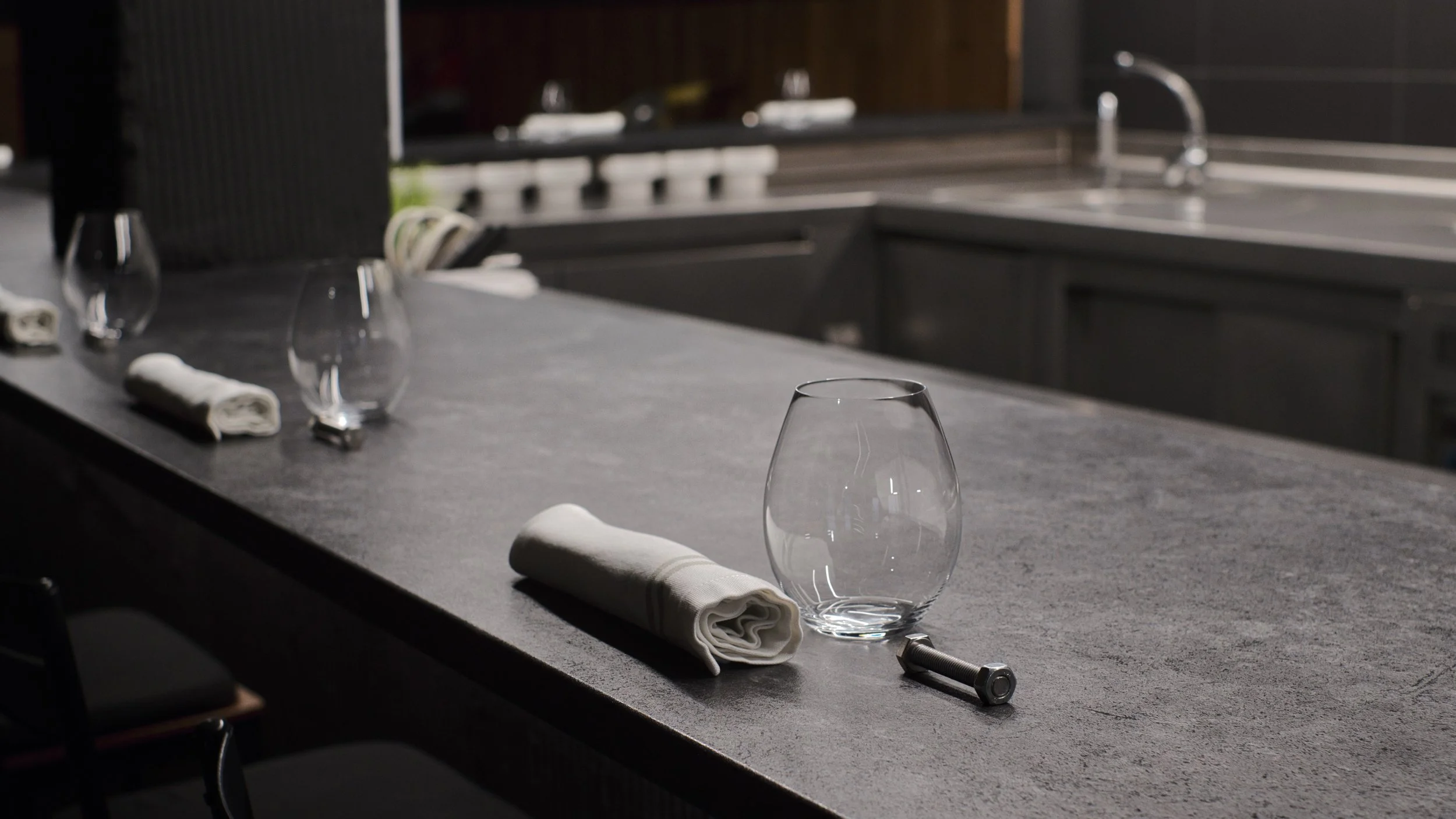 Una mesa de cocina con vasos, utensilios de mesa enrollados y un napkin en un ambiente de cocina moderna.