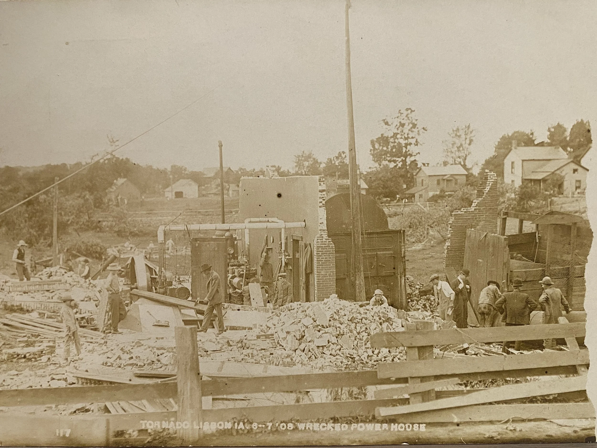 Historical photograph of a tornado wrecking power house in Lebanon, Missouri, with workers and debris.
