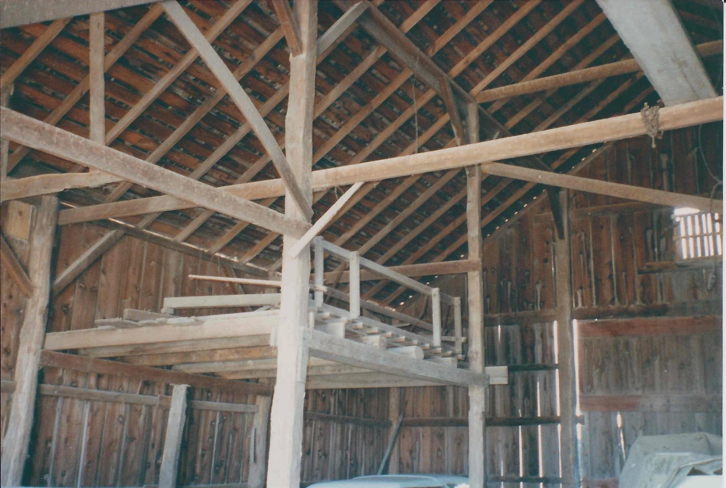 Interior of a wooden barn with exposed beams and a loft platform.