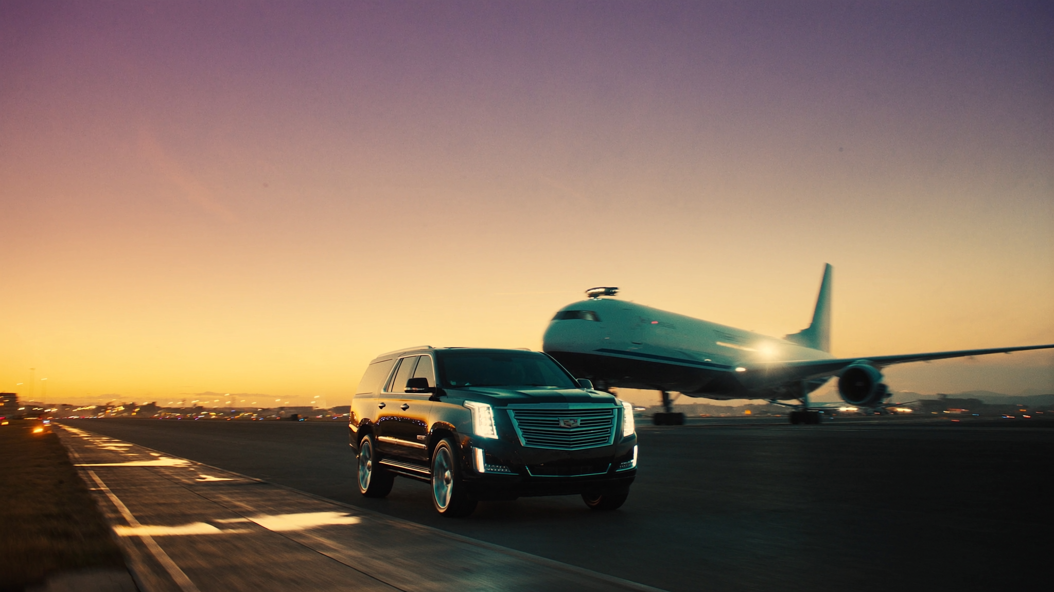 Black Escalade parked next to airplane