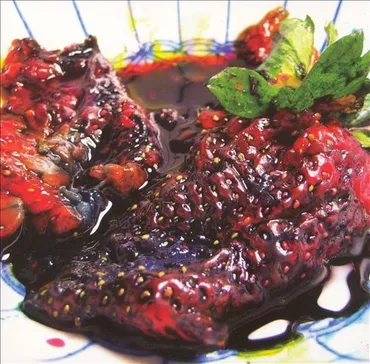 Fresh blackberries that appear to be soaked in a dark syrup or juice, garnished with a sprig of mint. Album art.
