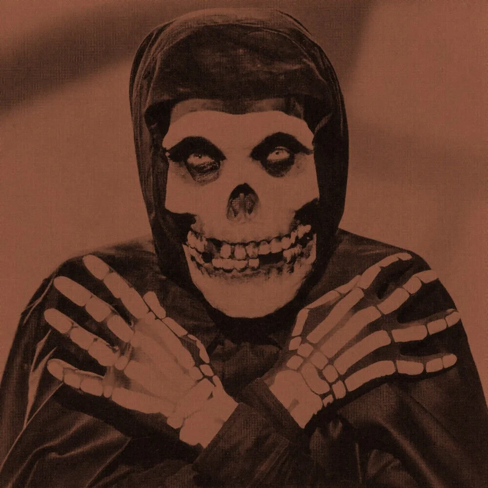 A person dressed in skeleton-themed costume with a skull mask, crossing their arms over their chest on the "Collection II" by The Misfits album cover.