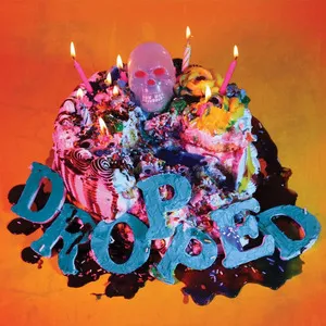 A colorful birthday cake with pink and yellow frosting, decorated with candles, a skull ornament, and blue letters spelling 'DROPPED' in front. Album art.