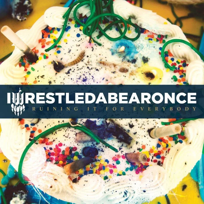 A birthday cake with white icing, colorful sprinkles, and scattered burnt candles. The cake features a label with the text 'iwrestledabearonce' and the phrase 'Ruining It For Everybody' underneath. Album art.
