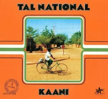 A boy riding a bicycle in a rural area with trees and houses in the background, on a sandy road. Text reads "Tal National" and "Kaani". Album Art.