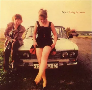 Two young women posing in front of a vintage car on an open road with a hazy sky, labeled 'Beirut Gulag Orkestar.' Album art.