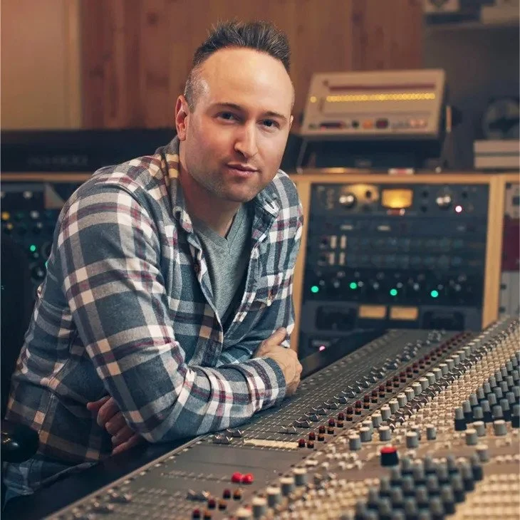 Man sitting at a music mixing console in recording studio.