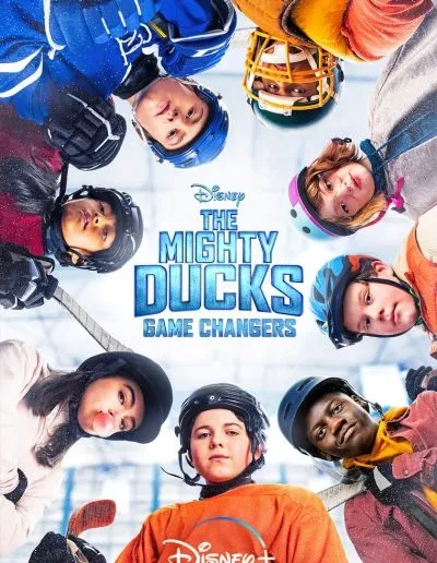 A group of young girls in hockey gear, looking down at the camera in a circle, with a background of a hockey rink, for the Disney series 'The Mighty Ducks: Game Changers'.