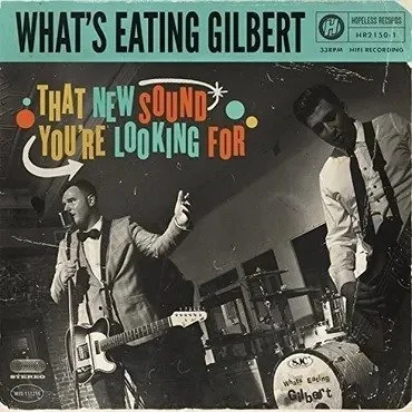 Album cover featuring two men performing; one is playing guitar and singing into a microphone, the other is standing beside him. Text at the top reads 'What's Eating Gilbert,' and below, colorful text says 'That New Sound You're Looking For.'
