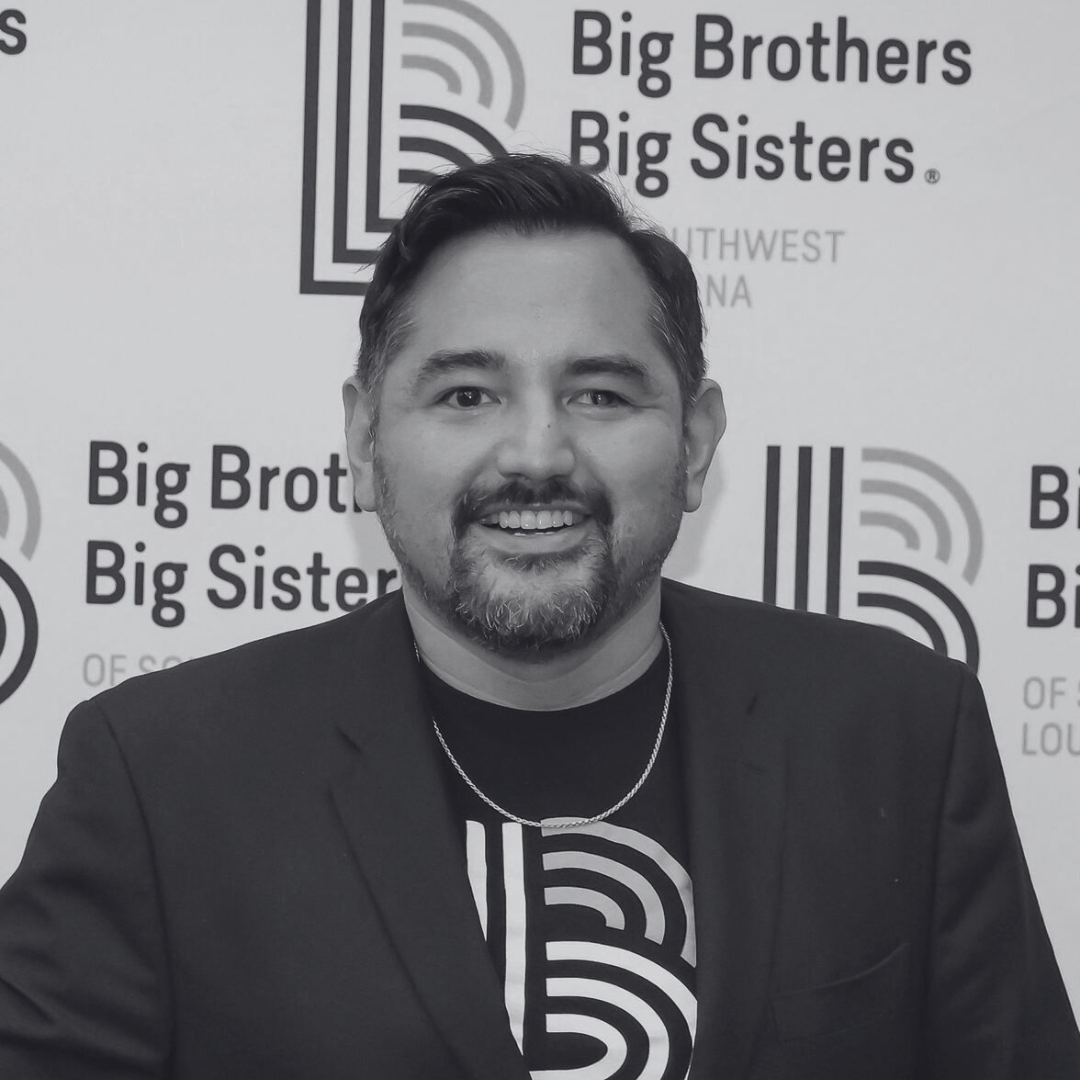 Person smiling in front of a Big Brothers Big Sisters backdrop.