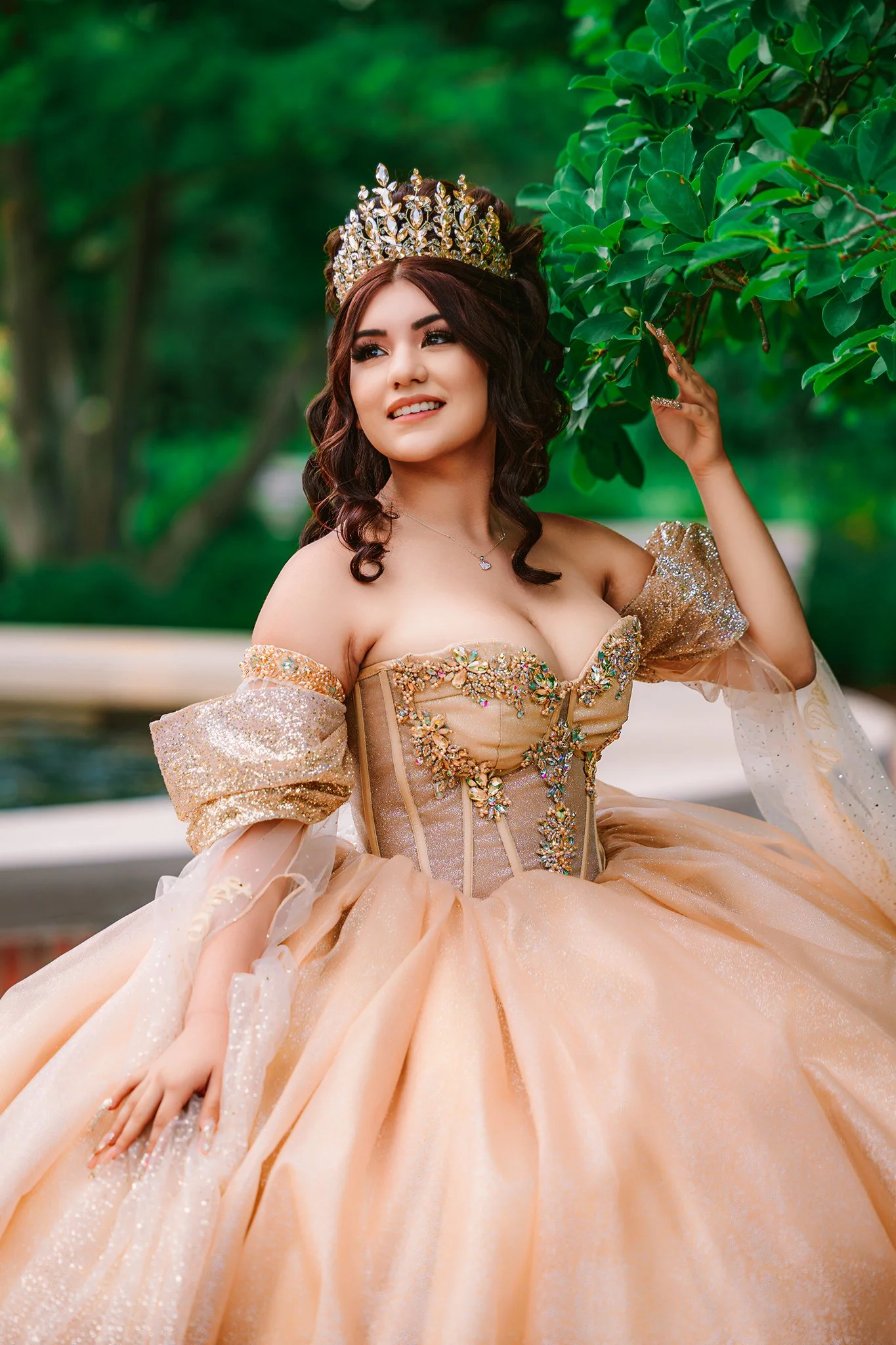 Quinceañera wearing a crown and gold gown in an outdoor portrait by Timeless Fifteens