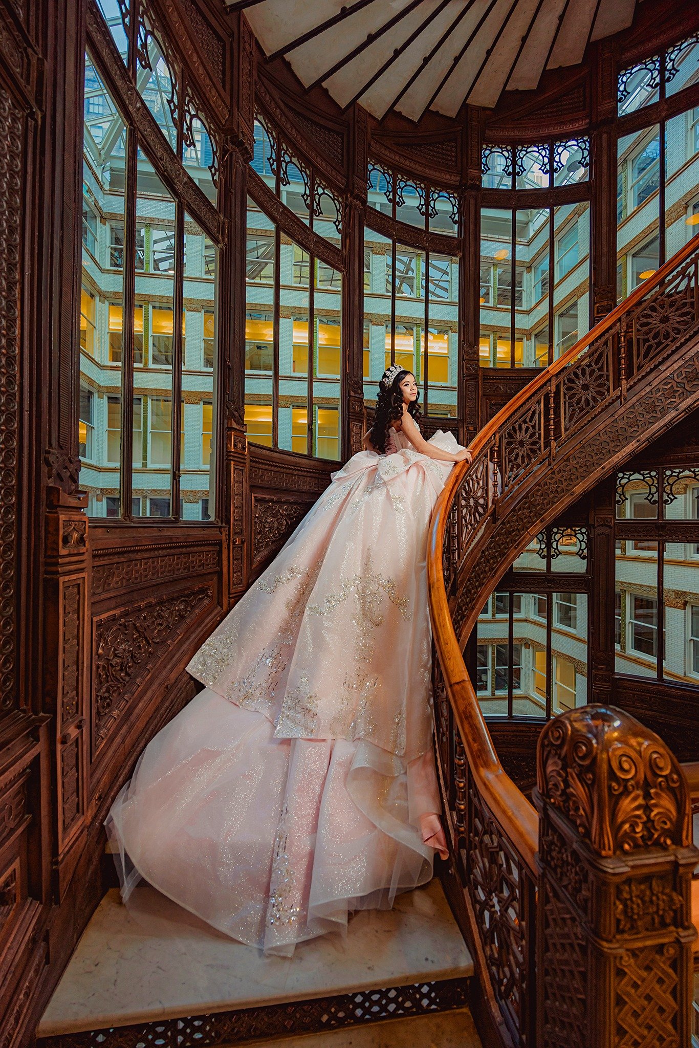 Alia in a blush quinceañera gown on an ornate wooden staircase