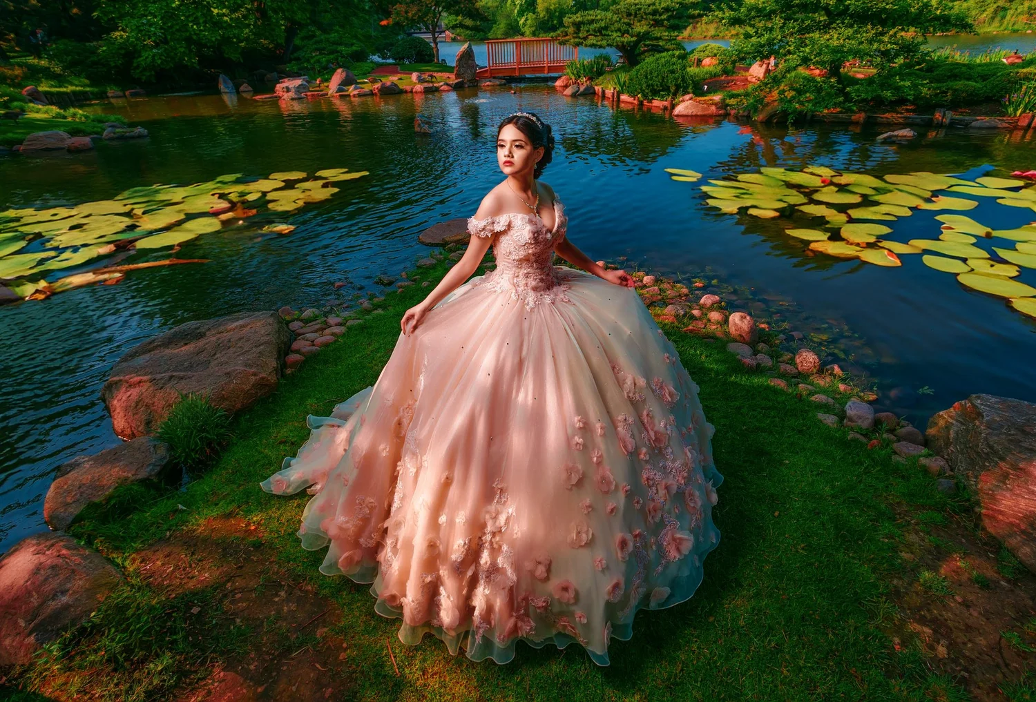 Quinceañera portrait in an elegant gown beside a garden pond
