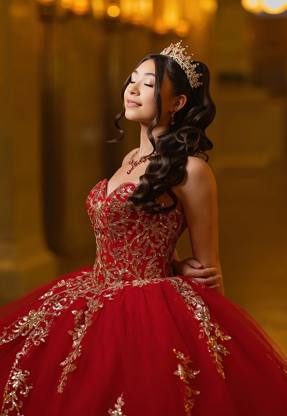 Quinceañera portrait with a jeweled crown and red and gold gown in warm light