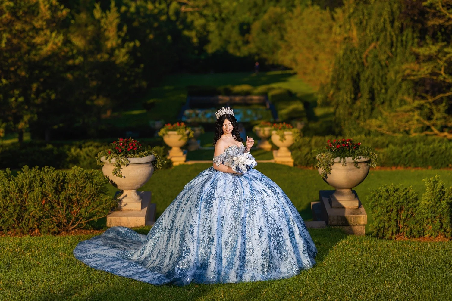 Quinceañera in a blue gown during an outdoor portrait session in a formal garden