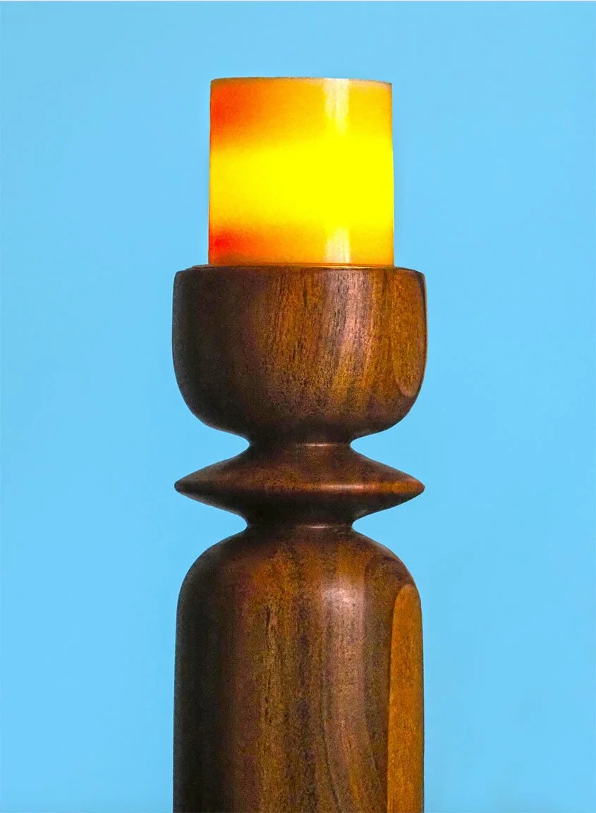 A  World Market wooden candlestick holder set against a bright blue background. Image by Margaret Waage Product photography.