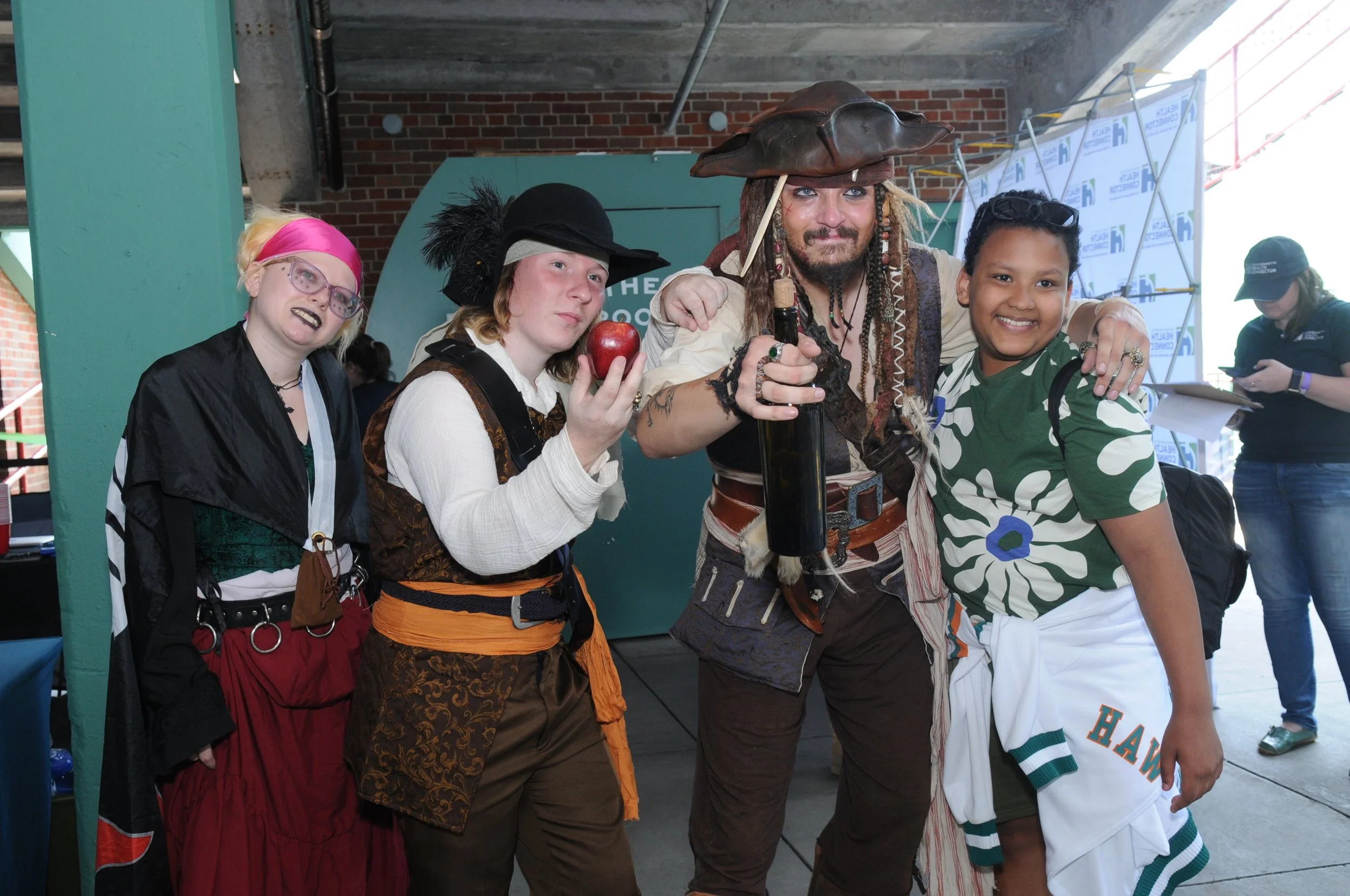Group of people in pirate costumes and casual attire posing at an event.