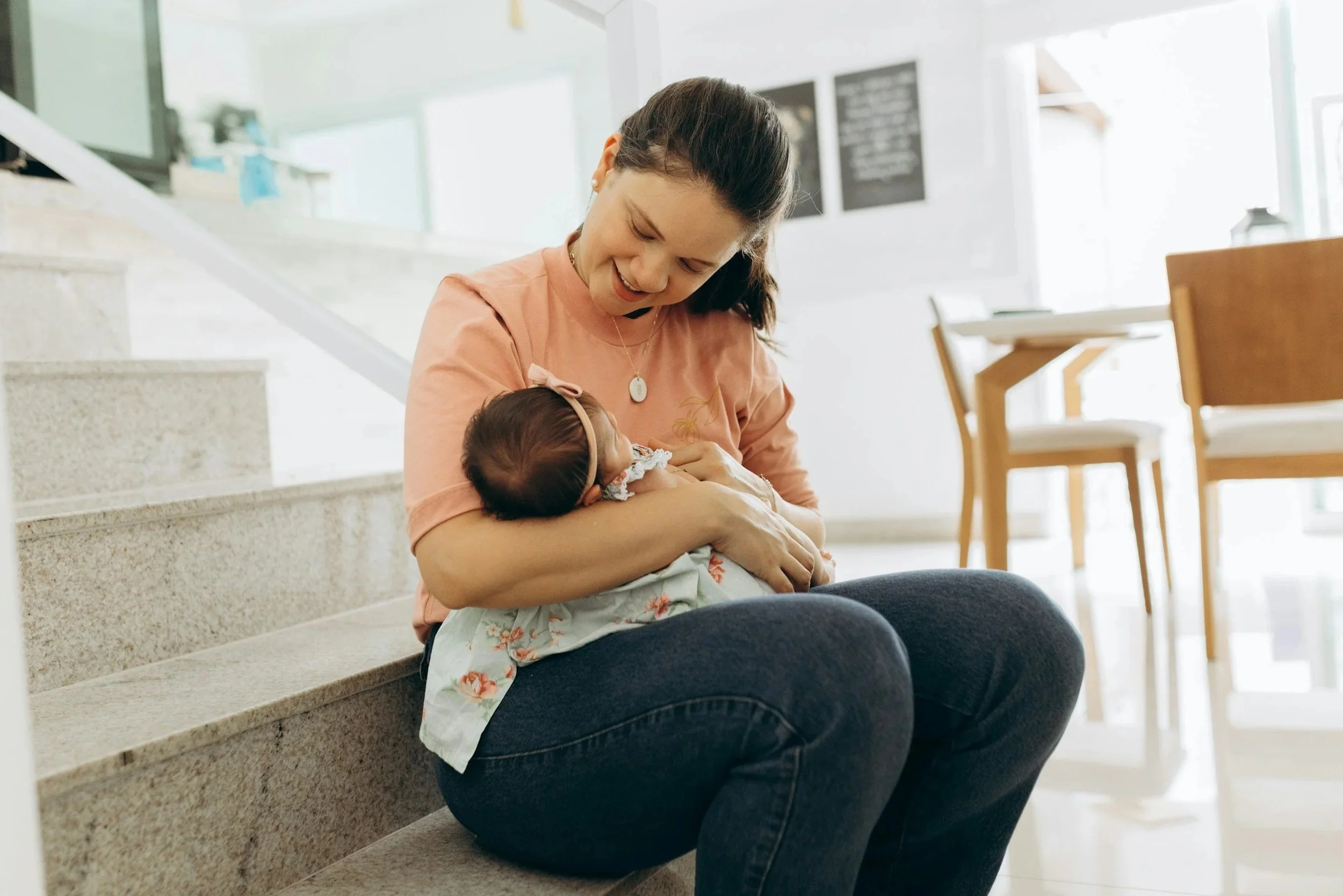 A woman sitting on stairs holding a newborn baby in her arms.