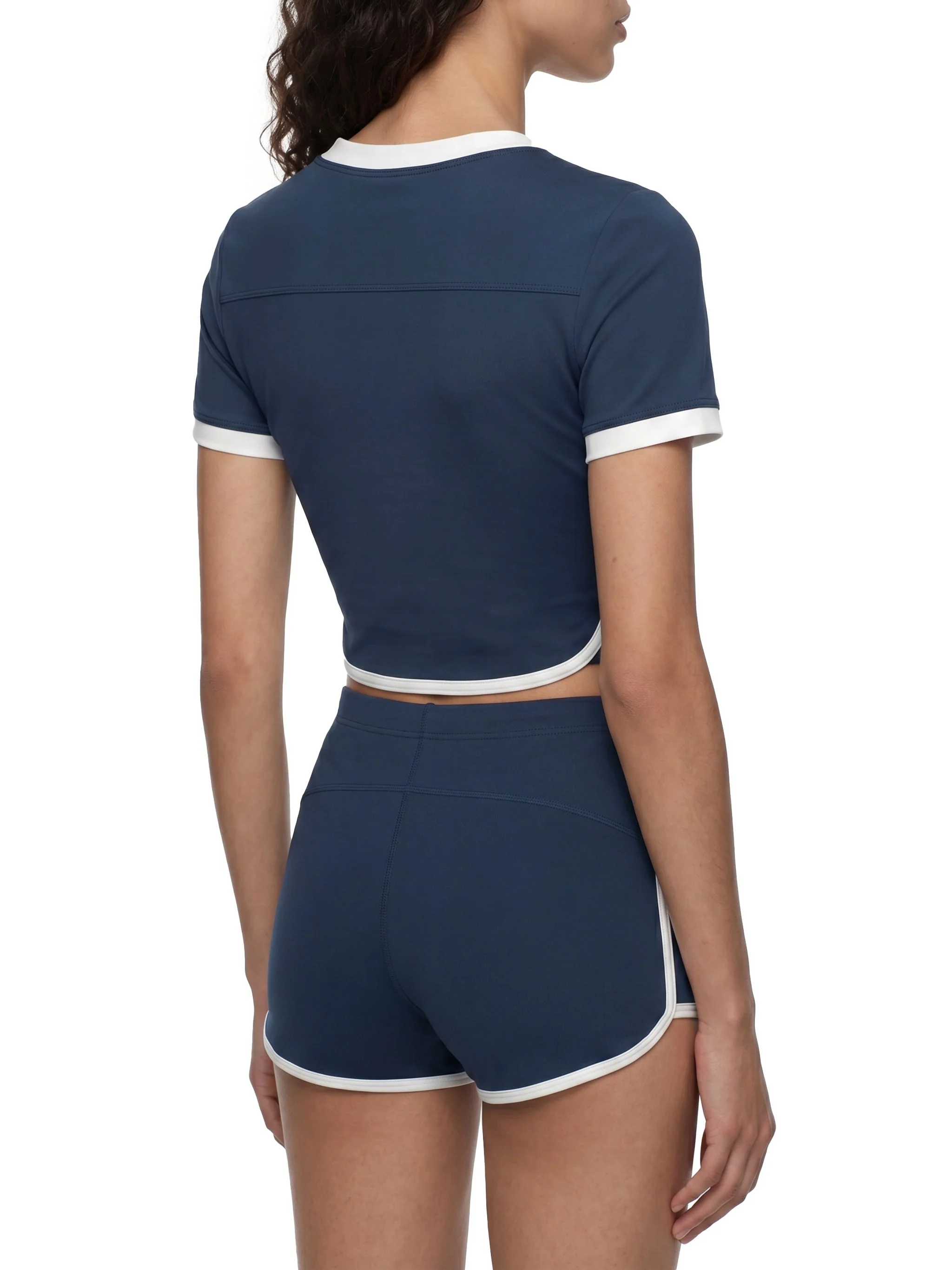 Back view of a woman wearing a navy blue sports bra and matching shorts with white trim.