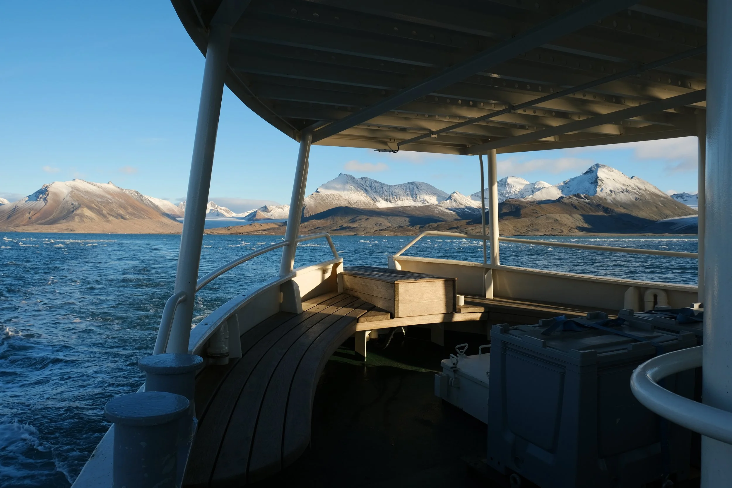 Rear part of  MV Ulla Rinman with a sunny view of mountains and sea of Svalbard.