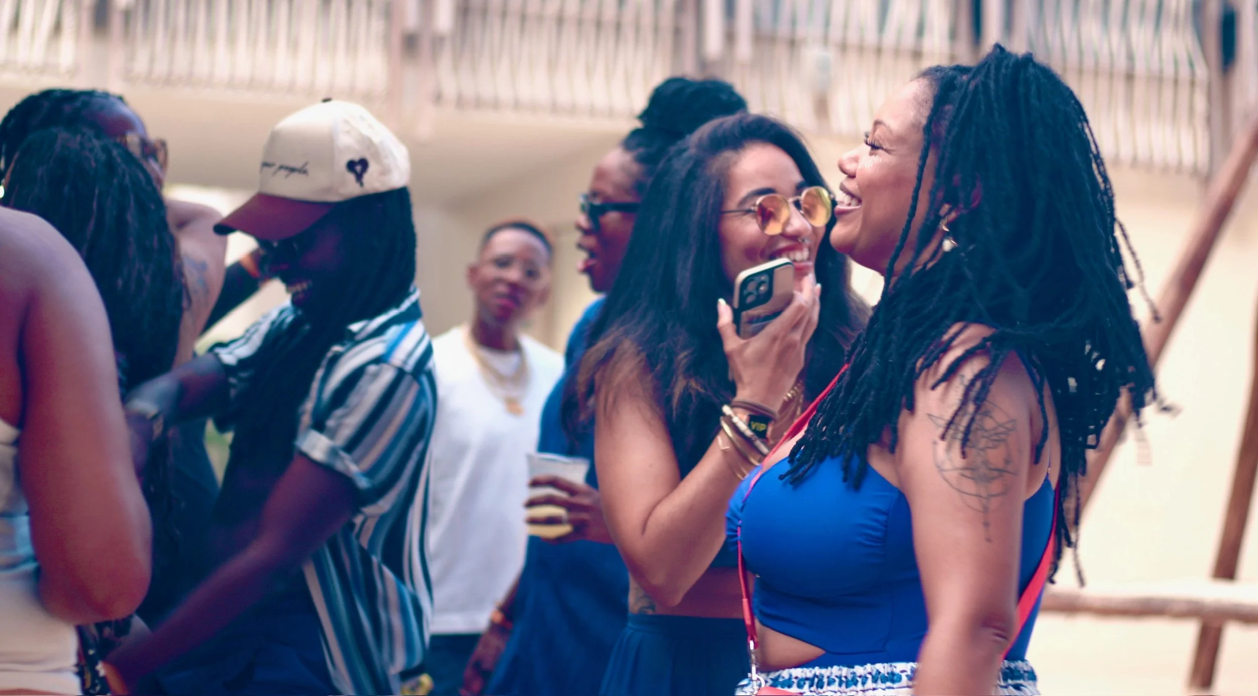 Group of diverse black and brown queer women enjoying conversation and laughter at an outdoor gathering.