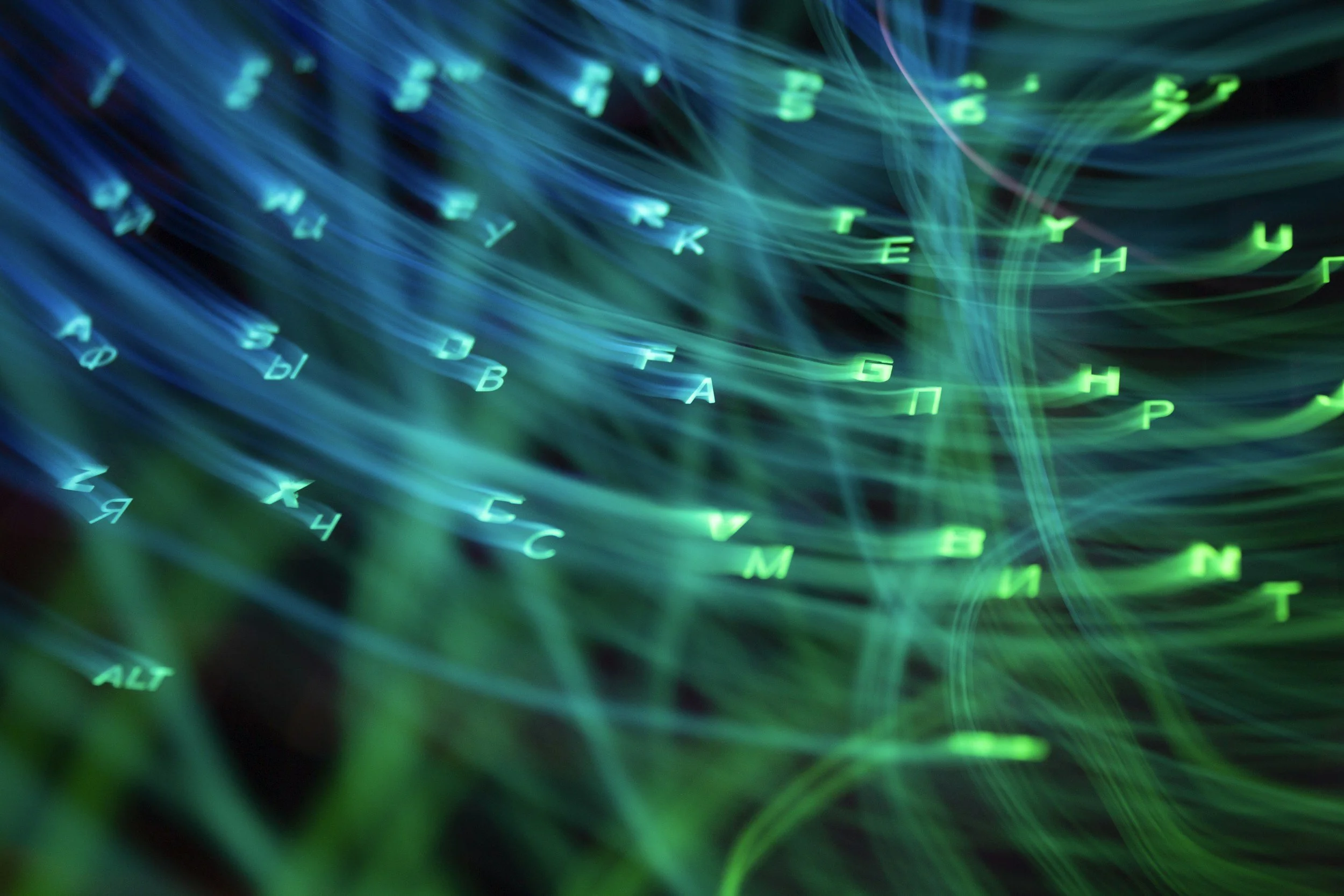 Tastiera illuminata con luci al neon verdi e blu, con lettere e numeri che sembrano fluttuare in un effetto di movimento.