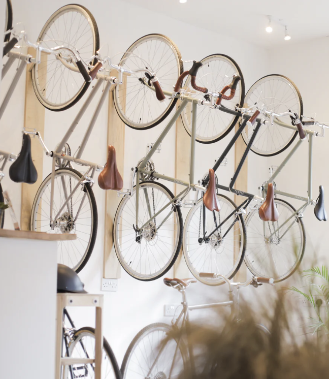 Several bicycles with brown saddles mounted on a vertical wall display in a shop.