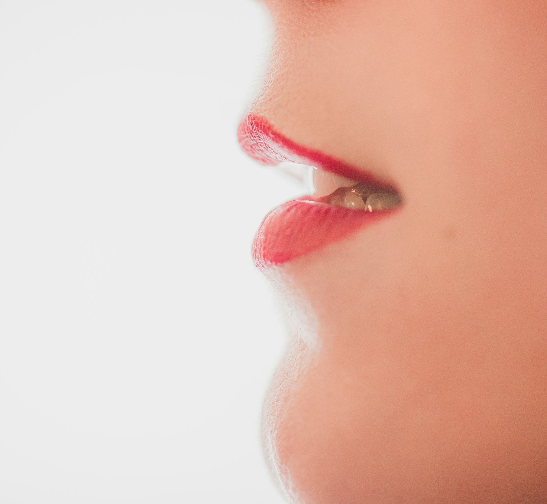 Close-up of a person's lips with red lipstick, partially parted.