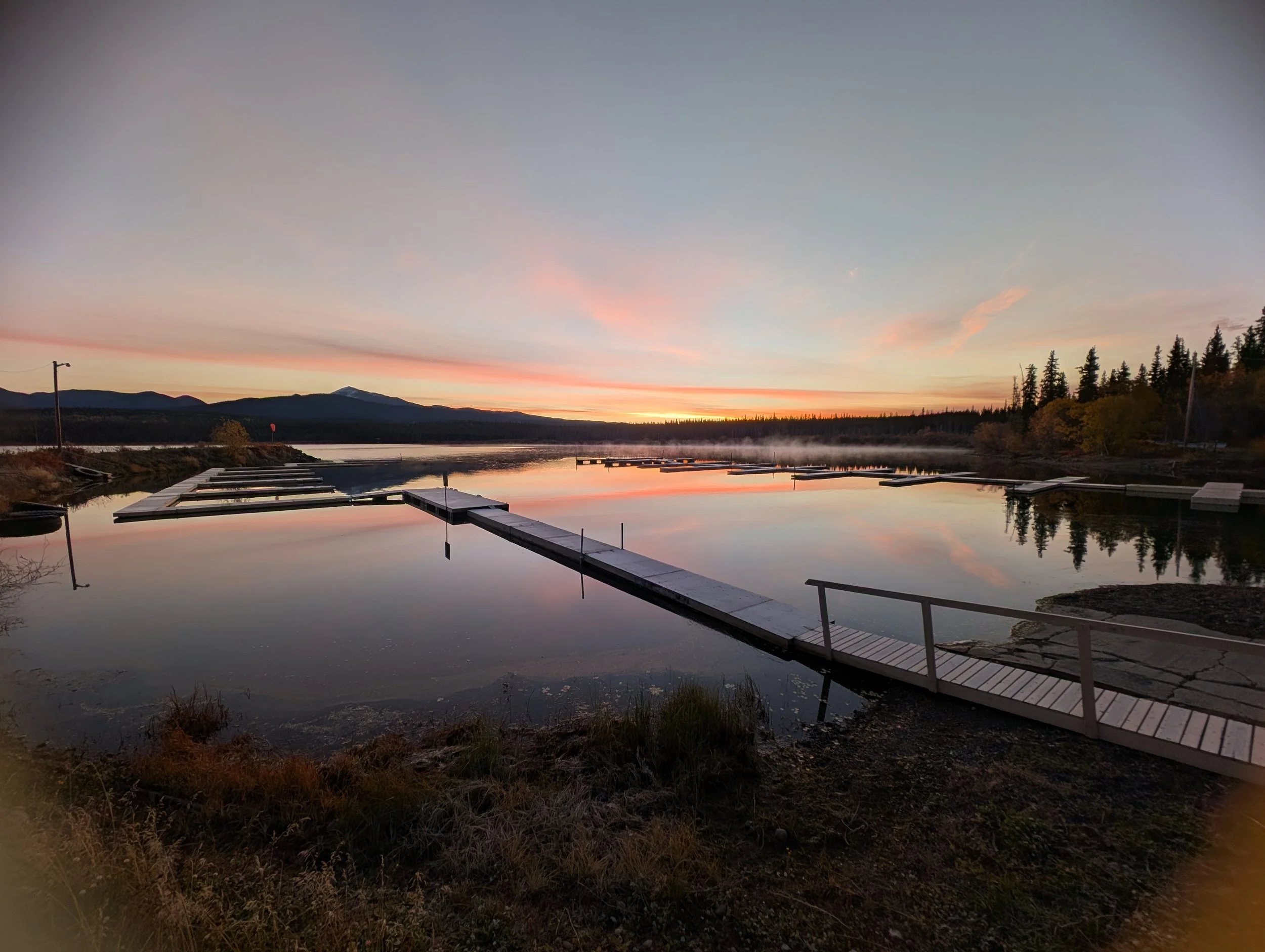 Sunrise over a small marina with steam rising from the lake.