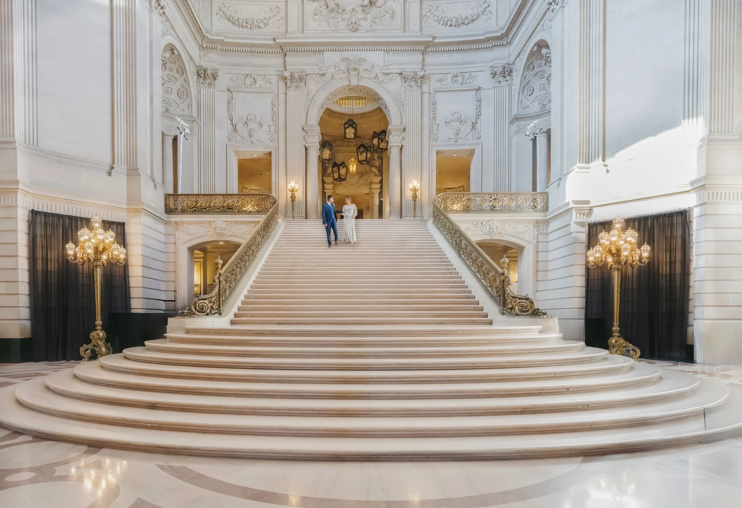 Wedding couple standing on the grand staircase inside San Francisco City Hall.