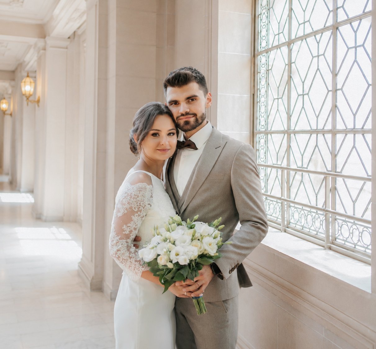 Wedding couple standing beside a tall window at San Francisco City Hall
