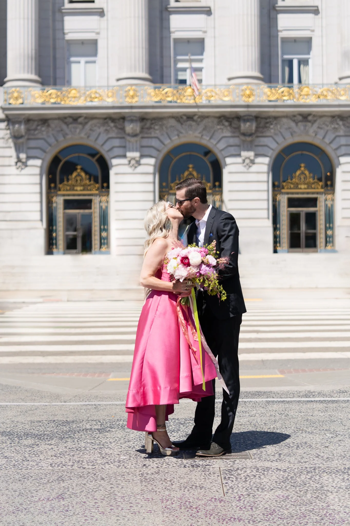 Wedding couple sharing a kiss outside San Francisco City Hall.