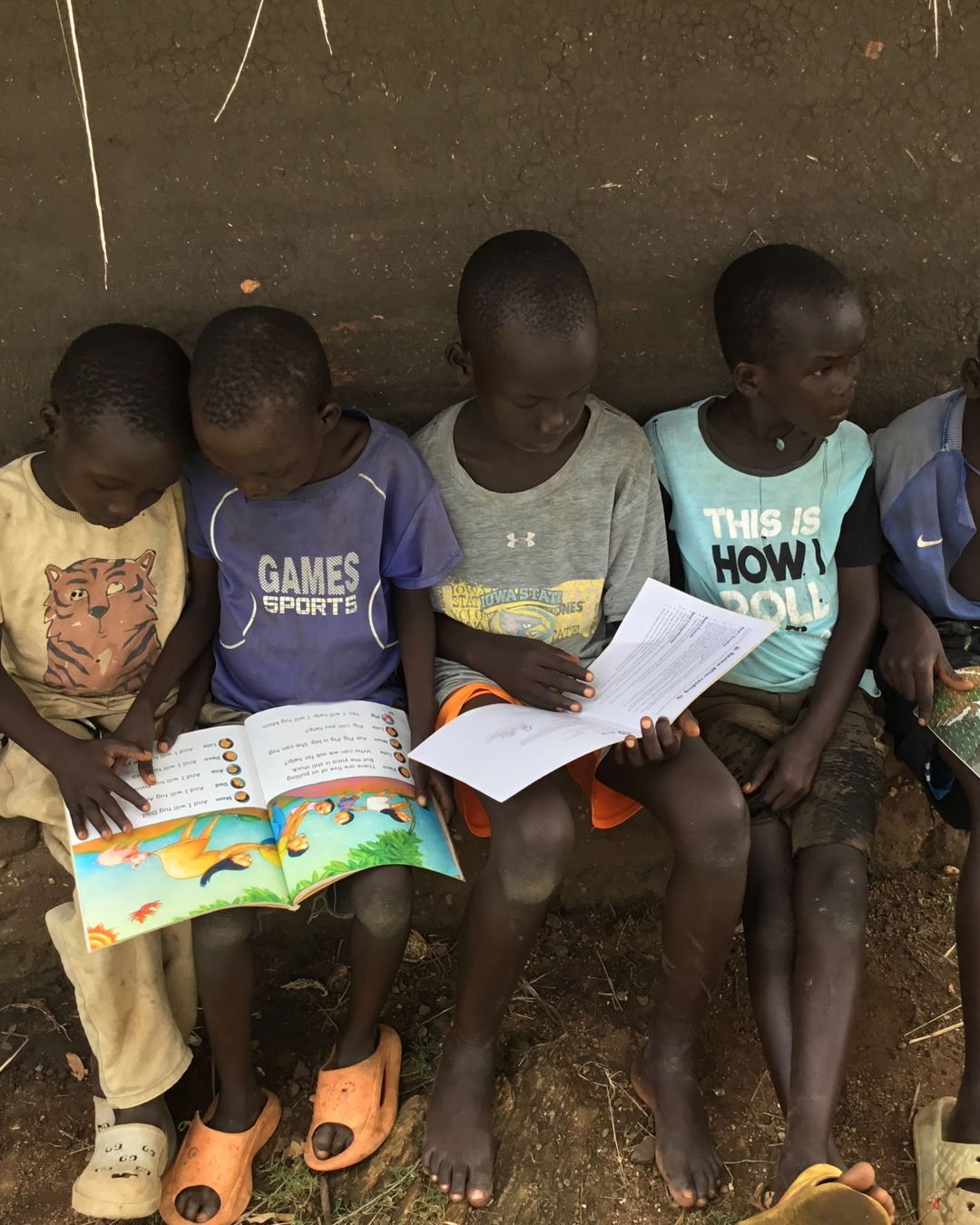 Young explorers cluster on the earthy ground, eyes sparkling over lively pages. Tiny voices echo with excitement as they sound out words, poke at vivid drawings, or lean in to retell tales to wide-eyed buddies. Even grown-ups drop by, circling around