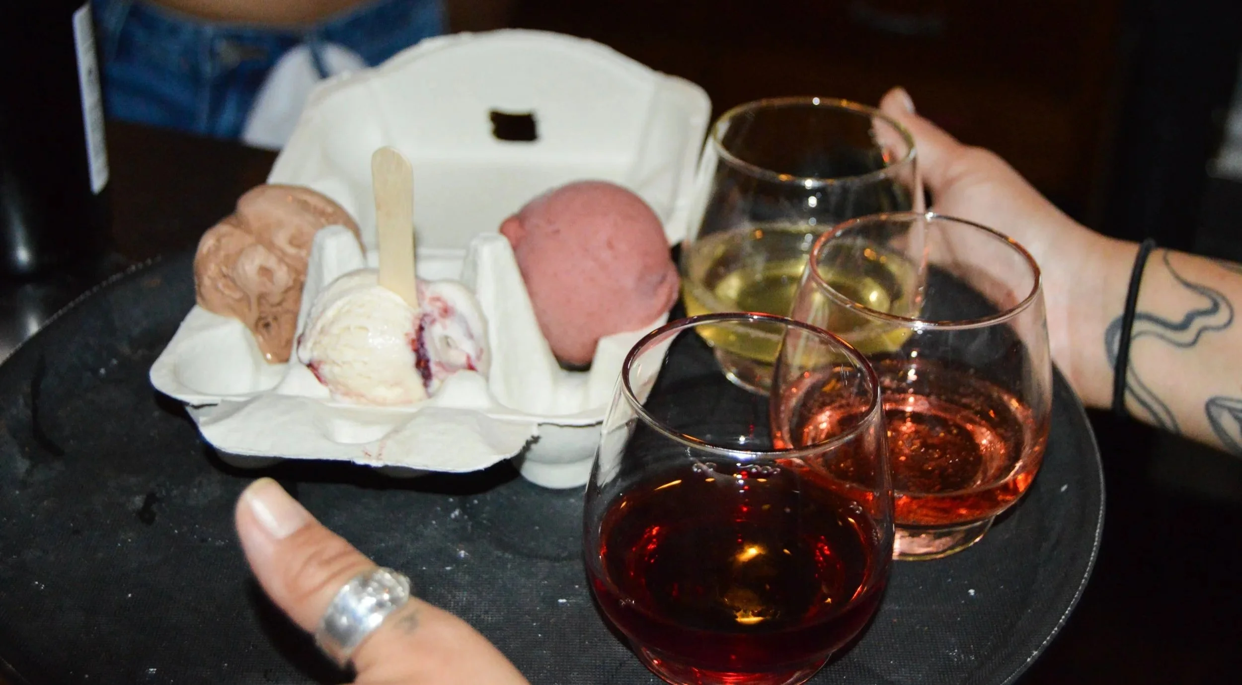 A tray with three glasses of rosé wine and a container of three ice cream scoops in different flavors.