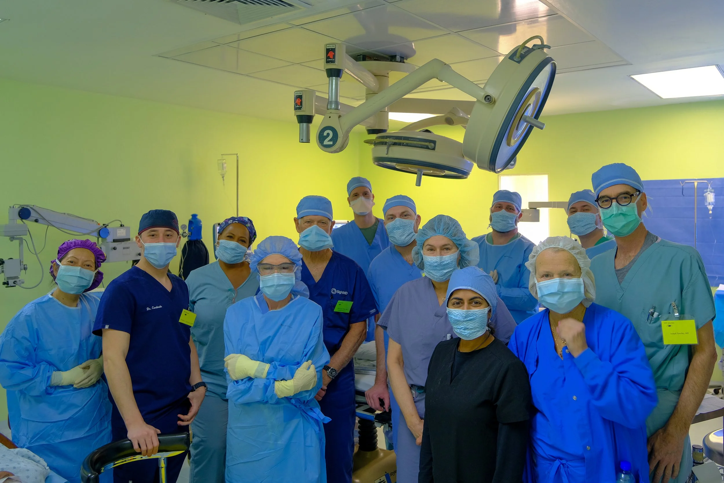 Group of medical professionals in scrubs and masks in a hospital operating room.