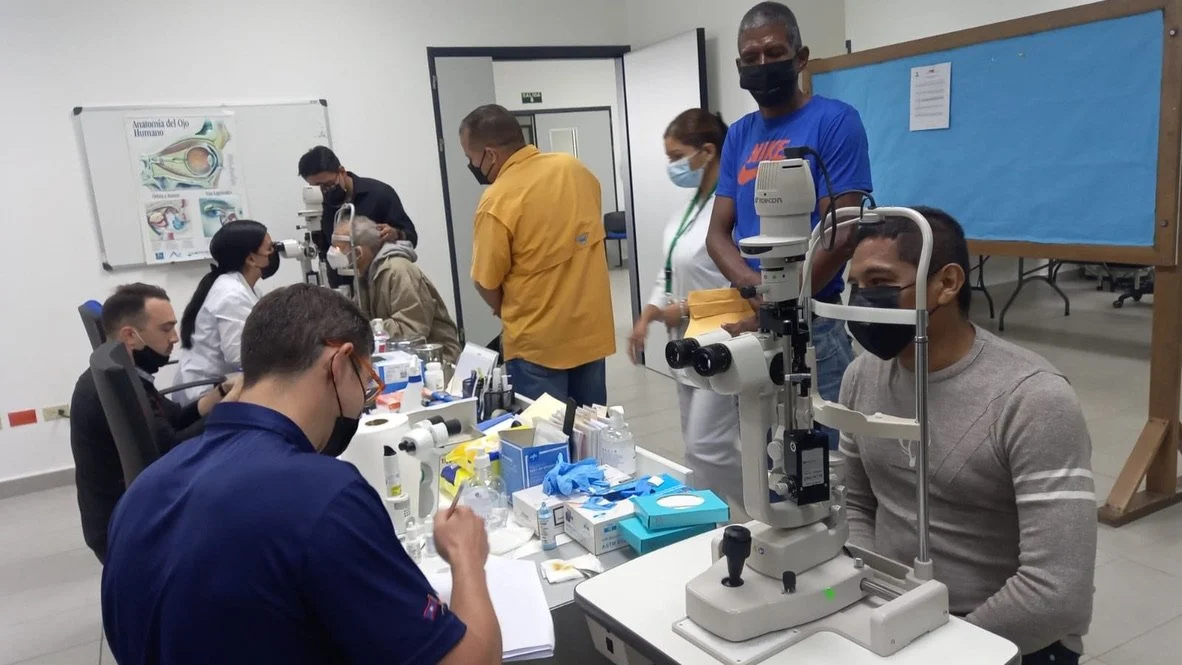 People in an eye clinic having eye examinations, various equipment and staff assisting patients.