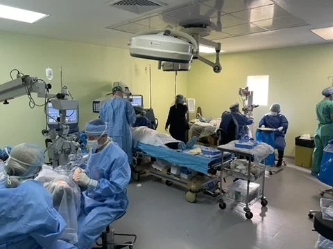 Surgeons and medical staff conducting parallel surgeries in an operating room.