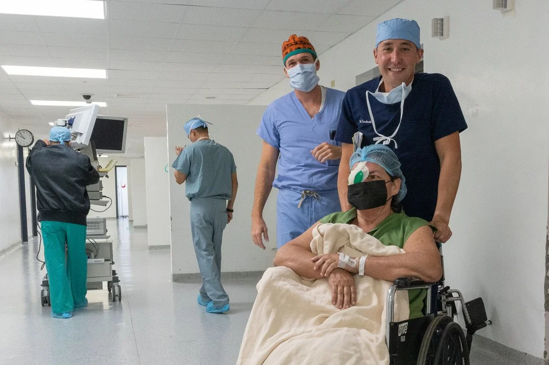 Healthcare professionals with a patient in a wheelchair wearing medical attire and masks in a hospital corridor. eye Surgery.