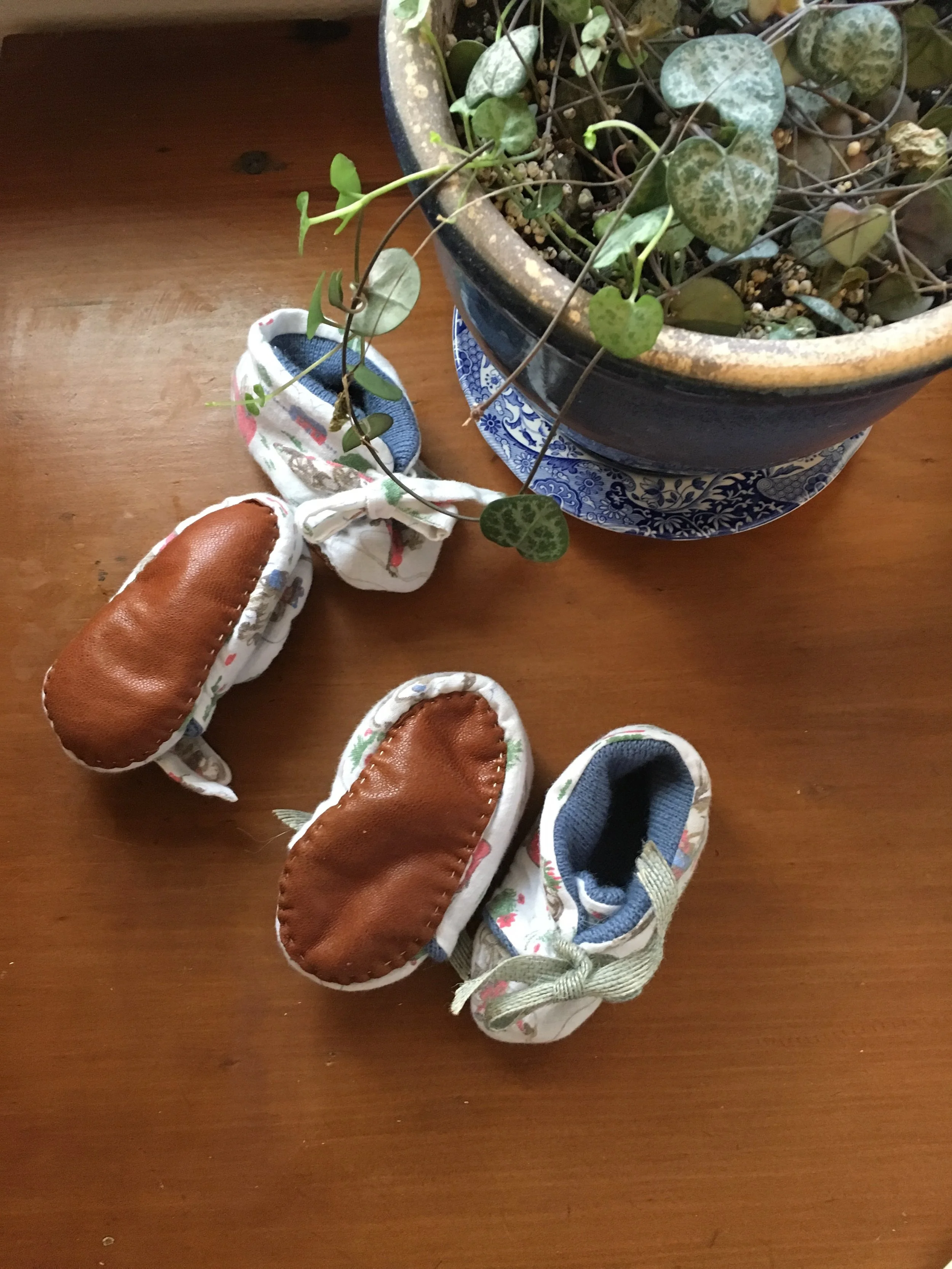 Underside of little people's slippers made from a locally foraged wool jumper, Cath Kidston cloth bag and damaged leather handbag 