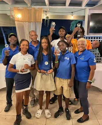 Group of eight people, including children and adults, celebrating with drinks indoors at a party or gathering.