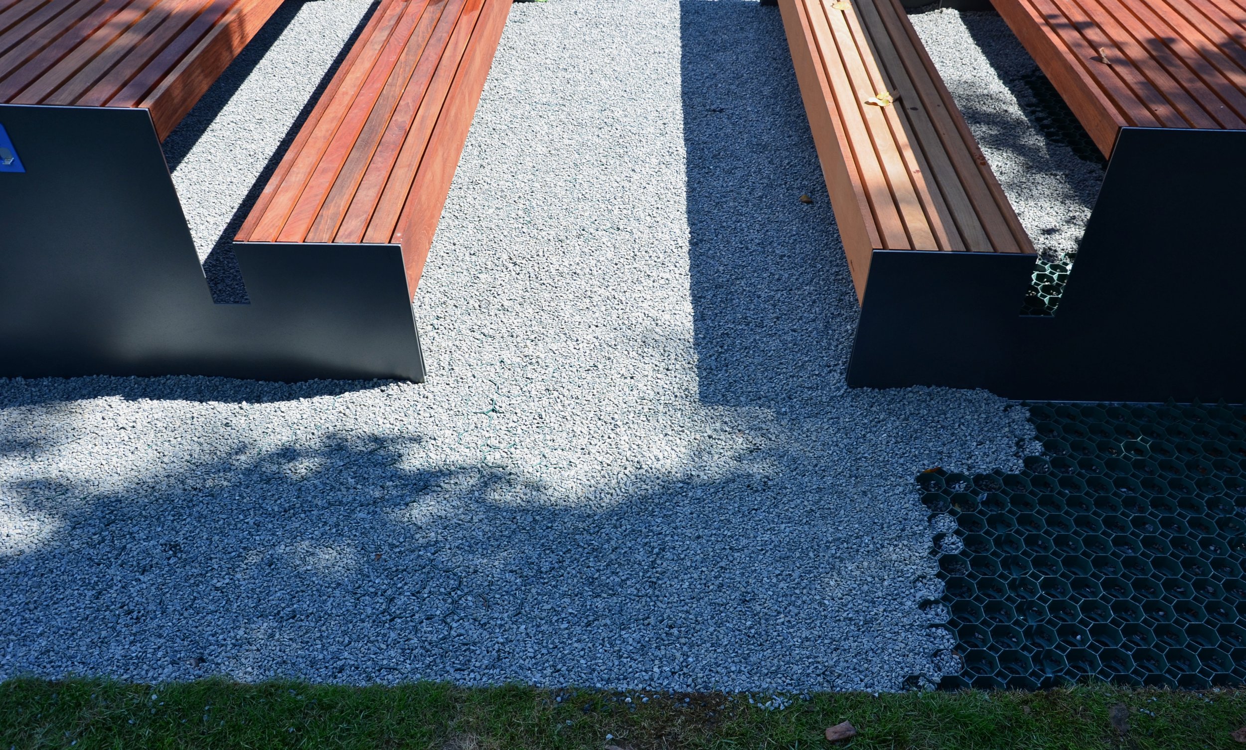 Wooden benches with metal frames on a gravel surface