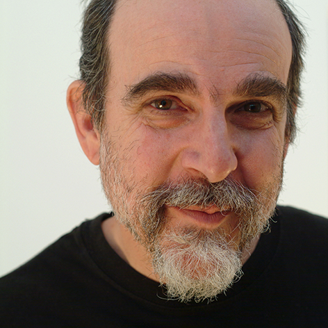 Man with a beard and receding hairline wearing a black shirt, smiling slightly.