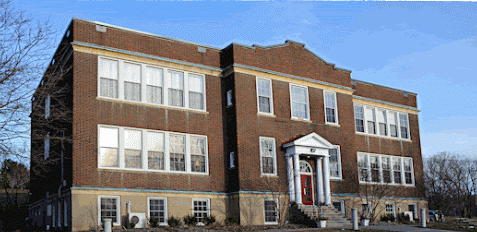 Historic brick school building with three stories and large windows