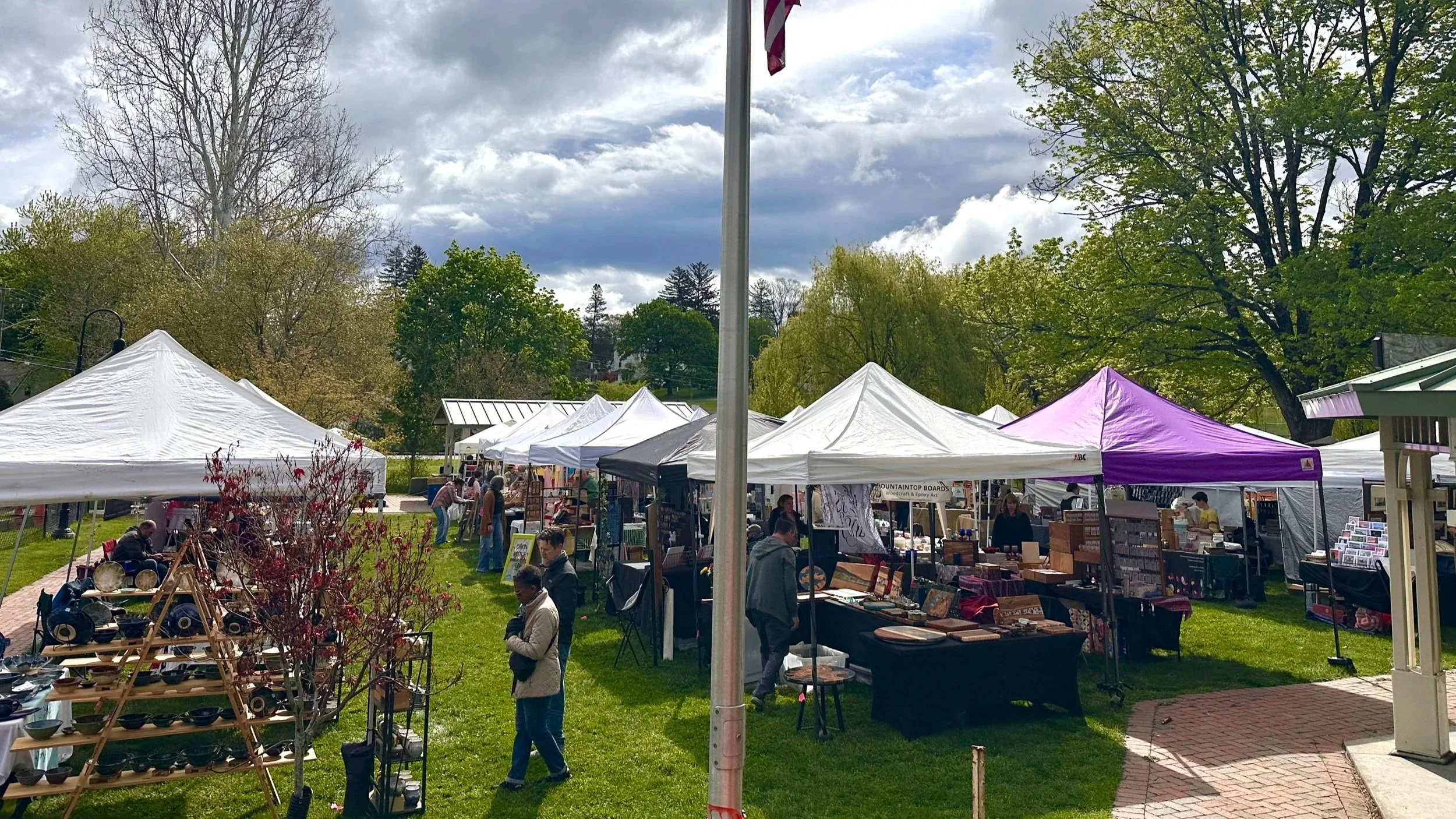 Outdoor holiday market with tents and people, church in background