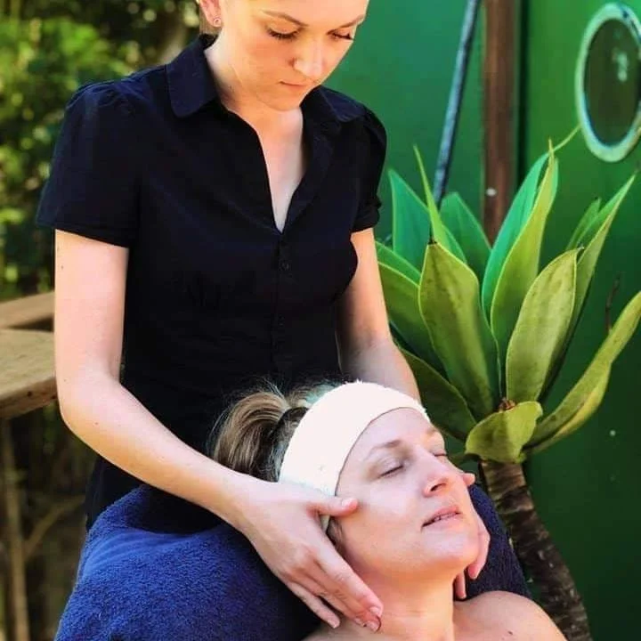Woman receiving a relaxing neck massage in a serene outdoor setting.