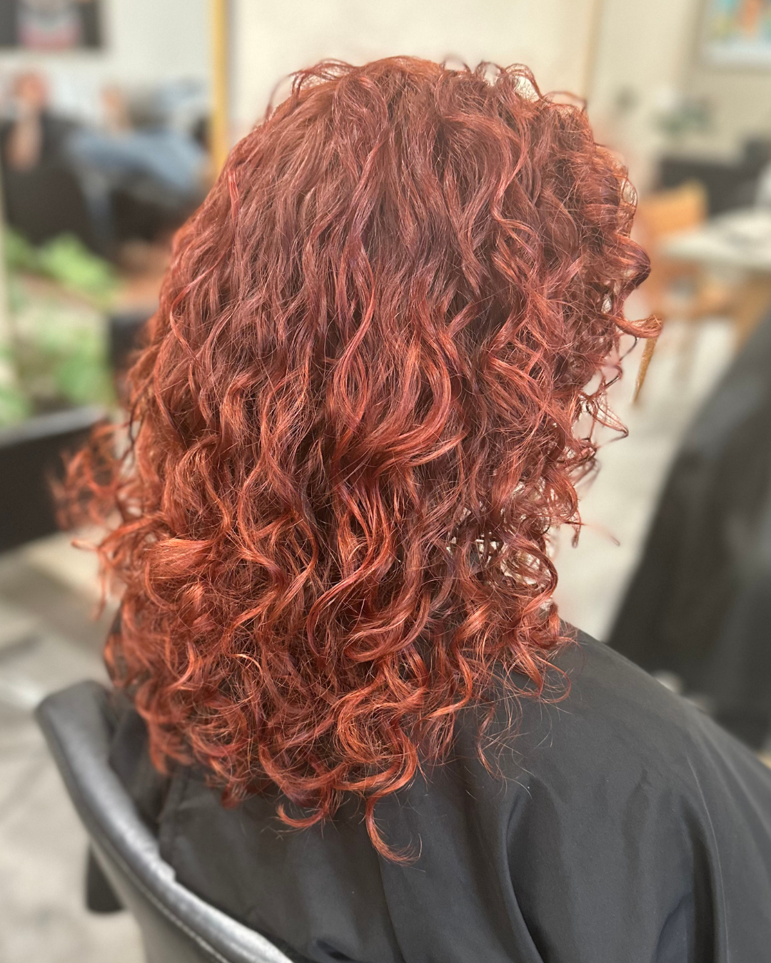 Woman with curly, red hair sitting in a salon chair