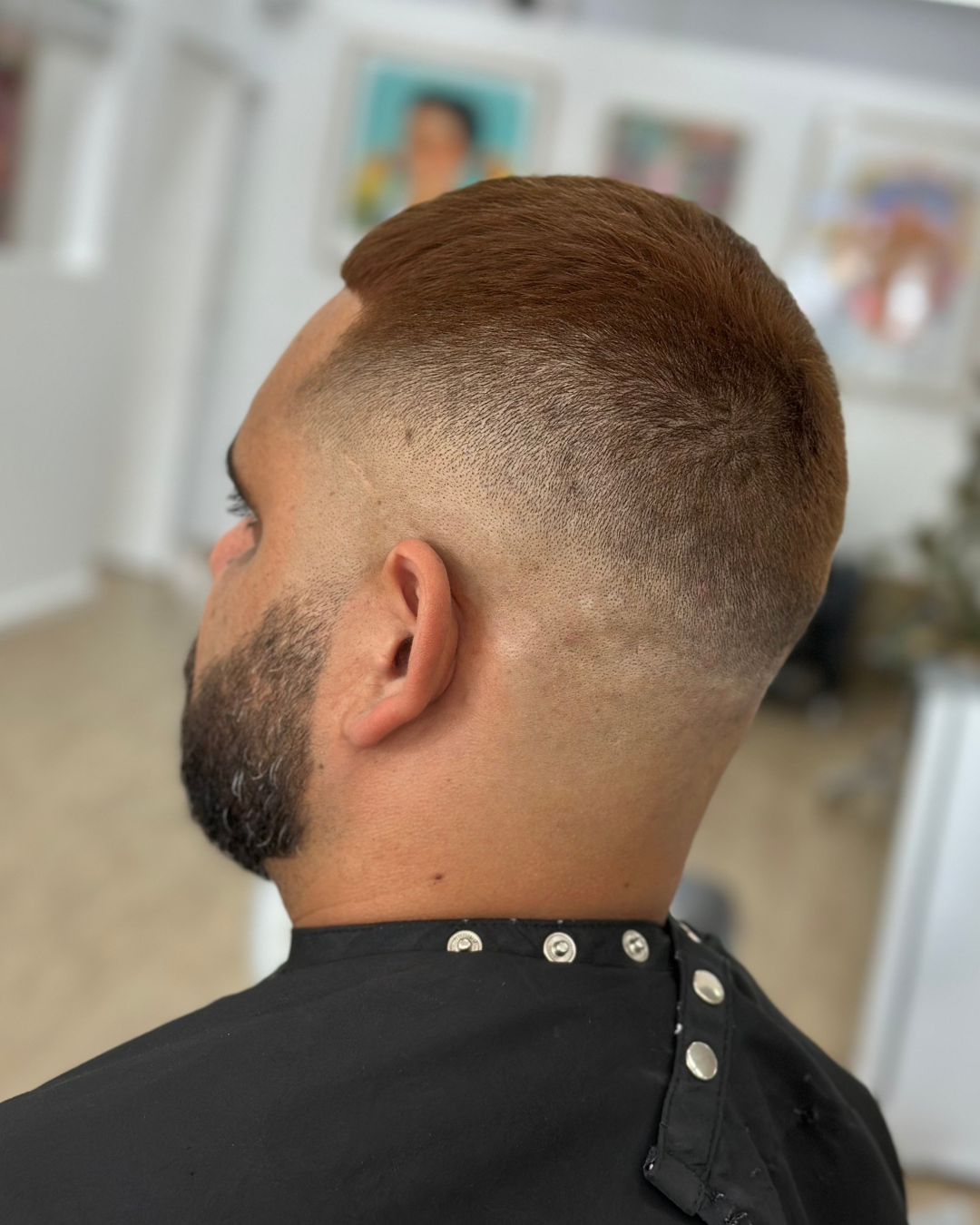 Side view of a man with a fresh buzz cut hairstyle in a barber's shop.