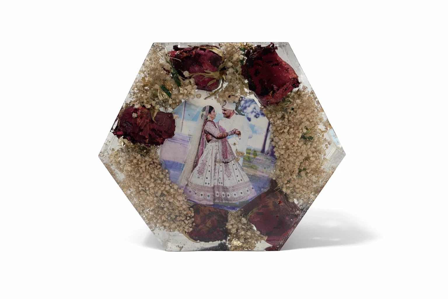 Hexagonal glass block with dried flower petals and an embedded photo of a couple in traditional wedding attire.